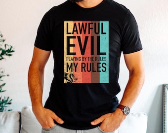 May include: Black t-shirt with the text "LAWFUL EVIL" in a rectangular design with a dragon graphic. The text "PLAYING BY THE RULES MY RULES" is below the main text. The design features a color block of orange, red, brown, and teal.