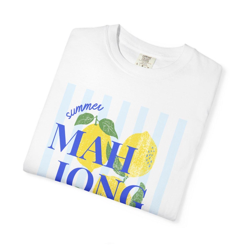 May include: A white short-sleeve t-shirt featuring a graphic of yellow lemons with green leaves over light blue vertical stripes. The text "summer" is written in blue script above the blue block-lettered word "MAHJONG" printed across the lemons.