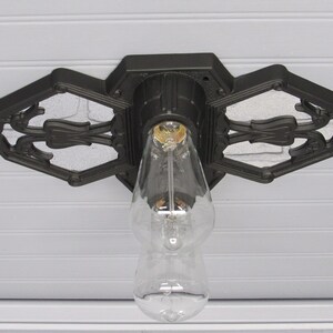 May include: Black ceiling light fixture with a decorative, ornate design. The fixture has a single light bulb and is mounted to a white ceiling.