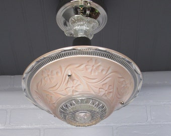 May include: A pink glass ceiling light fixture with a floral design. The light fixture has a chrome finish and a clear glass shade.