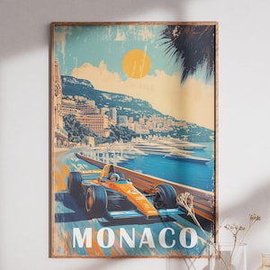 May include: Vintage-style poster print featuring an orange race car speeding along a coastal road in Monaco. The artwork includes a bright yellow sun, blue water, and the word "MONACO" in large letters.