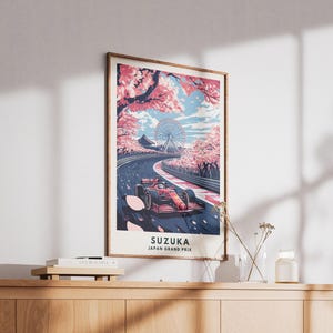 May include: Framed art print featuring a Formula 1 race car on a track in Suzuka, Japan. The artwork showcases a vibrant scene with cherry blossoms, a Ferris wheel, and the text "SUZUKA JAPAN GRAND PRIX". The color palette includes red, pink, and blue.