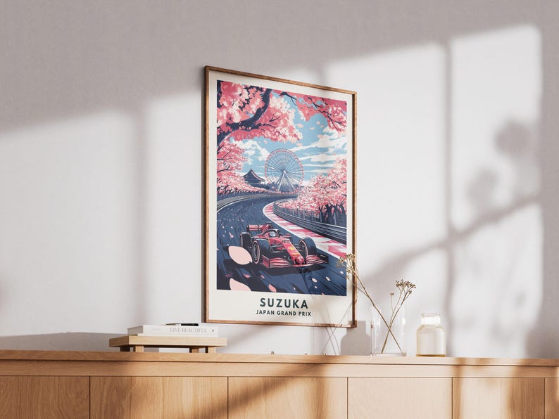 May include: Framed art print featuring a Formula 1 race car on a track in Suzuka, Japan. The artwork showcases a vibrant scene with cherry blossoms, a Ferris wheel, and the text "SUZUKA JAPAN GRAND PRIX". The color palette includes red, pink, and blue.