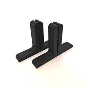 Puede incluir: Dos soportes de plástico negro para elevar un monitor o un portátil. Los soportes tienen forma de L invertida con una ranura en la parte superior para sujetar el dispositivo.