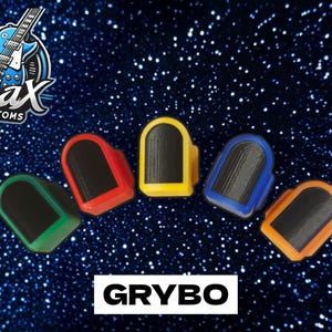 May include: Five guitar knobs with black centers and colored outer rings in green, red, yellow, blue, and orange. The logo Ajax Customs is in the top left corner, and the text GRYBO is centered at the bottom against a dark blue glitter background.