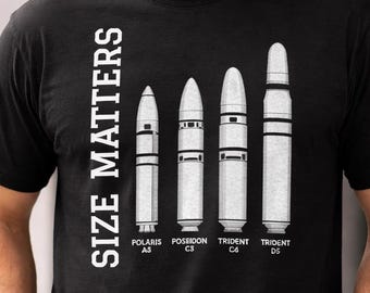 May include: Black t-shirt with the text "SIZE MATTERS" in white, alongside a graphic of five white missiles. The missiles are labeled "POLARIS A3", "POSEIDON C3", "TRIDENT C4", and "TRIDENT D5".