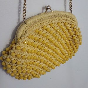 May include: A yellow beaded clutch purse with a gold chain strap.