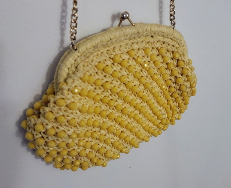 May include: A yellow beaded clutch purse with a gold chain strap.