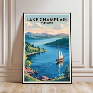 May include: Framed art print showing Lake Champlain, Vermont. The image features a sailboat on blue water, with green trees, hills, and mountains under a pastel sky. The words "Lake Champlain Vermont" are at the top of the print, in a black font.