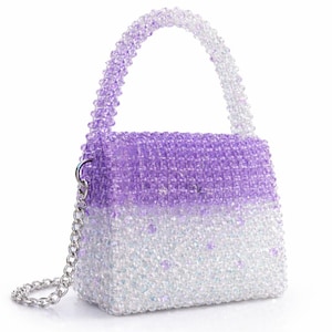 May include: A beaded handbag in a gradient of purple to white. The small purse has a top handle and a silver chain strap. The beads are iridescent, giving the bag a shimmering effect. The bag is a small, structured design.