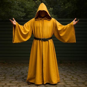 May include: Mustard yellow hooded robe with wide sleeves and a black belt. The robe is open in the front and has a hood that covers the head. The person is standing with arms outstretched. The robe is made of a soft, flowing fabric.