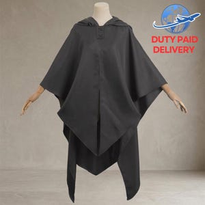 May include: A dark gray hooded cloak with a button closure at the neckline. The cloak has a cape-like design with long, flowing panels. The words "DUTY PAID DELIVERY" are in red text in the upper right corner.