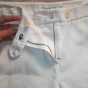 Puede incluir: Pantalón blanco con cierre de cremallera y botón. El pantalón tiene una pequeña etiqueta que dice "Christian Dior" y "42".