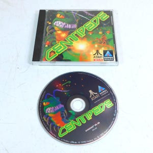May include: A Centipede PC game in a CD case. The cover art features a green, insect-like creature with the game title in green. The CD itself has the same design. The Atari and Hasbro Interactive logos are visible.