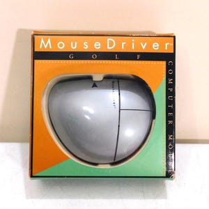 May include: A silver computer mouse in its original packaging. The box is orange, green, and black, with the words "MouseDriver" and "GOLF" printed on it. The mouse has a sleek, ergonomic design.