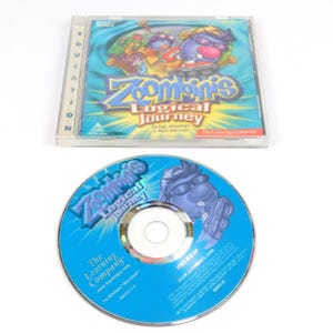 May include: A clear plastic CD jewel case and a matching blue CD for the computer game Zoombinis Logical Journey. The cover art features cartoon characters, the game title, and the text An Epic Adventure of Math and Logic. The disc is blue.
