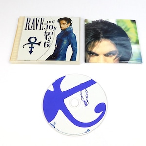 May include: A Prince Rave Un2 the Joy Fantastic CD album set including a clear plastic jewel case with cover art, a separate square booklet featuring a portrait of Prince, and a white circular disc with a large blue graphic and chain design.