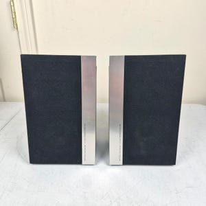 May include: Two rectangular speakers with black fabric grilles and a vertical silver metal strip on the right side of each unit. The silver strip features small black text that reads Onkyo Micro Fiber Diaphragm Hi-Fi 2-Way Speaker System D-012.
