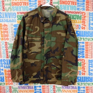 Könnte beinhalten: Ein Set aus drei Keramikbechern mit gesprenkelter, matter Oberfläche. Die Becher sind in den Farbtönen Creme, Hellgrau und Dunkelgrau gehalten. Jeder Becher hat ein schlichtes, modernes Design und einen abgerundeten Henkel. Die Becher sind aufeinander gestapelt.