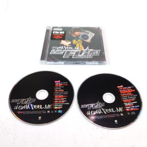 May include: A Lil' Flip "U Gotta Feel Me" CD album. The CD case is clear, with the album cover visible. Two black CDs are displayed, each with track listings and the album title. The album cover features a man holding a boombox.