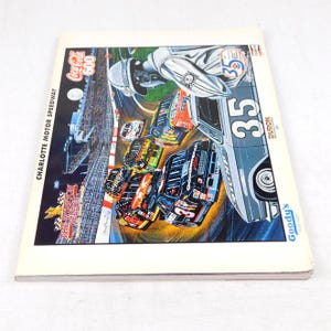 Könnte beinhalten: Ein Vintage-Rennprogramm der Coca-Cola 600 mit einer farbenfrohen Illustration von Rennwagen auf einer Rennstrecke. Das Cover enthält den Text "Charlotte Motor Speedway" und "The Winston Select". Die Nummer 35 ist prominent auf einem silbernen Rennwagen abgebildet.