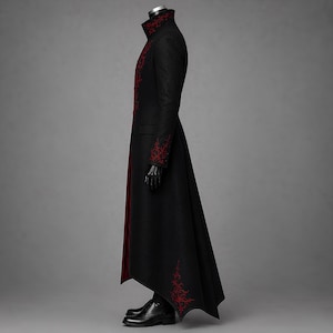 Side profile of a black Victorian Gothic tailcoat for men, designed with deep crimson accents, embroidered cuffs, a sharply raised collar and an elegant floor-length silhouette. The dramatic vampire longcoat creates a bold choice for Dracula costumes, Halloween celebrations, Renaissance festivals and alternative formal occasions.