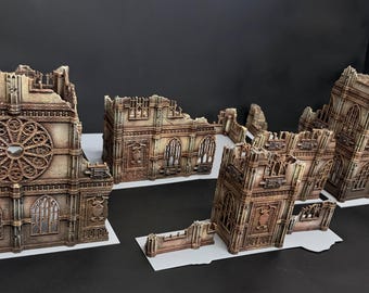 May include: A collection of miniature gothic cathedral ruins featuring weathered stone textures, intricate rose window detailing, pointed archways, and crumbling wall segments. The structures are painted in shades of brown and grey, designed for tabletop gaming terrain setups.