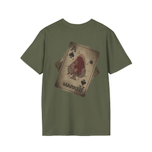 May include: Olive green t-shirt featuring a distressed Ace of Spades playing card design. The card has a fingerprint graphic and the word "MARKED" printed on it. The shirt is a casual wear item.