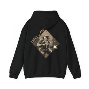 May include: Black hoodie featuring a sepia-toned graphic of a skeleton soldier firing a weapon, with the words "SPRAY AND PRA" above the image. The design is set within a diamond shape on the back of the hoodie. The hoodie has a hood and long sleeves.