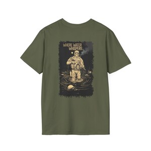 May include: Olive green t-shirt featuring a graphic of a soldier in water with the text "WHERE WATER WHISPERS". The illustration is in shades of tan, black, and white. The soldier is wearing military gear.