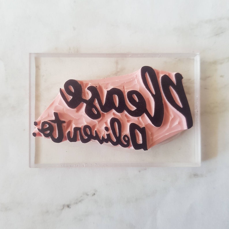 May include: A pink rubber stamp with the text "Please deliver to" in black lettering.