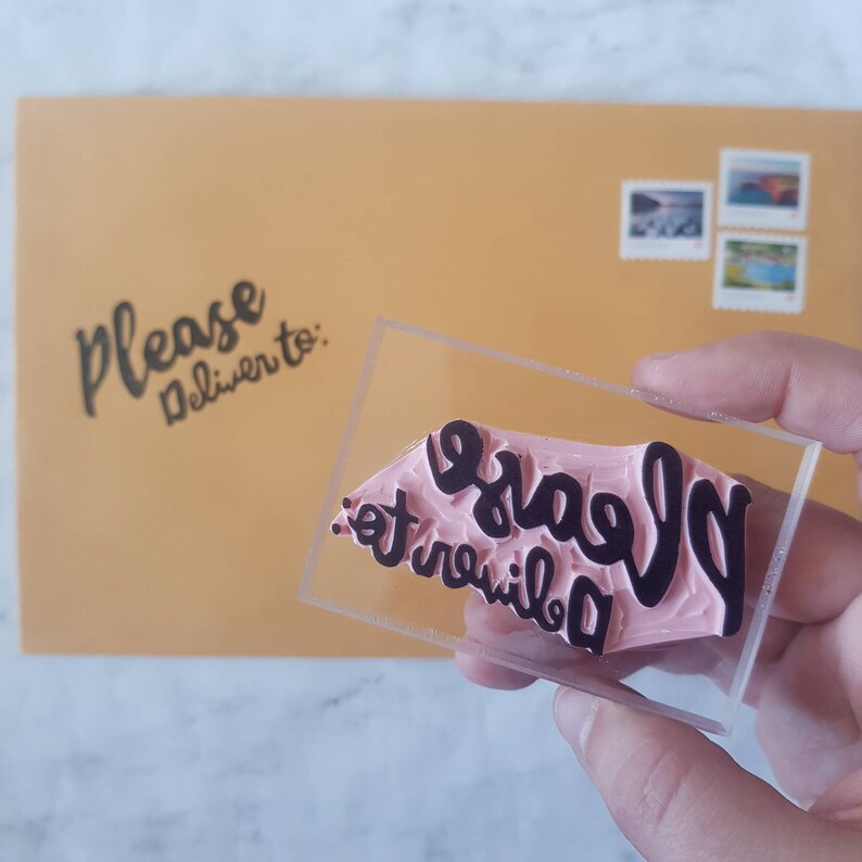 May include: A clear acrylic stamp with a pink rubber surface. The stamp reads "Please deliver to:" in black lettering.