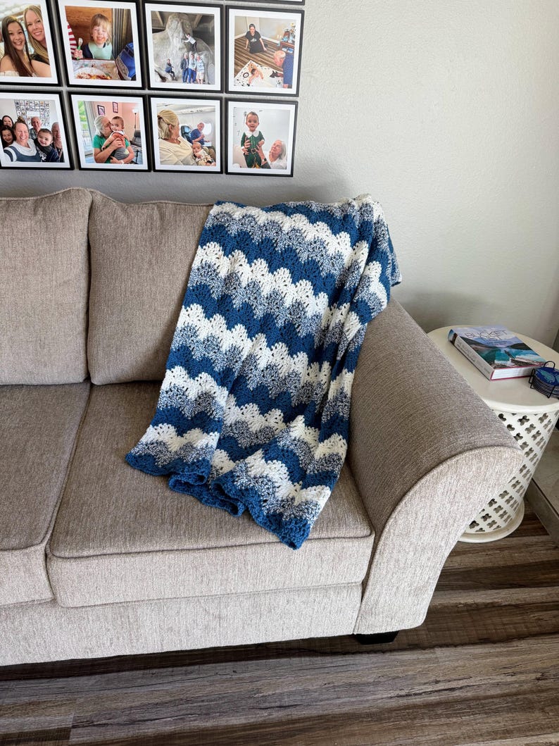 May include: A blue and white crocheted blanket with a wavy pattern is draped over a light gray couch.