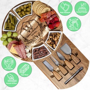 May include: A wooden charcuterie board with a circular serving area and a rectangular section for cheese knives. The board has small white bowls filled with olives, pickles, nuts, and other snacks. The center is engraved with the names "Wilson, Emma & Richard, EST. 2023".