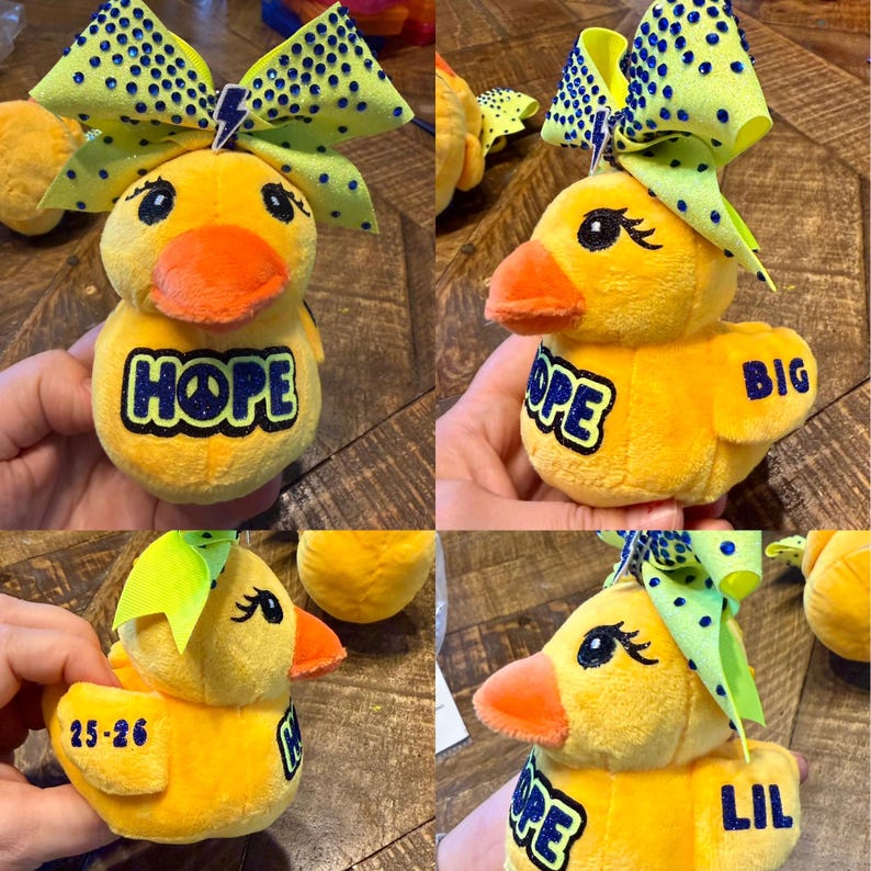 May include: A plush yellow duck toy with an orange beak and a large bow. The bow is yellow with blue polka dots and a lightning bolt. The duck has the word "HOPE" in blue letters. The duck is a cheerful and fun item.