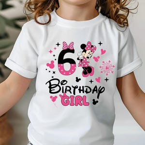 K&ouml;nnte beinhalten: Wei&szlig;es T-Shirt mit Minnie Mouse-Motiv, der Zahl 6, Herzen und dem Text "Birthday Girl" in Schwarz und Pink. Das T-Shirt hat hochgekrempelte &Auml;rmel und ist f&uuml;r ein Kind konzipiert.