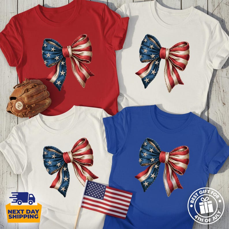 May include: Four short-sleeved t-shirts in red, white, and blue colors, each featuring a central graphic of a bow with a stars and stripes pattern. A brown leather baseball glove and a small American flag are positioned near the shirts.