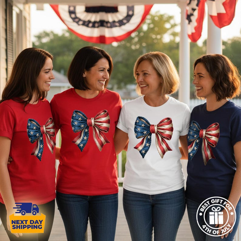 May include: A collection of short-sleeved t-shirts in red, white, and navy blue, each featuring a large, central graphic of a decorative bow patterned with the stars and stripes of the American flag. The shirts are worn by four individuals.