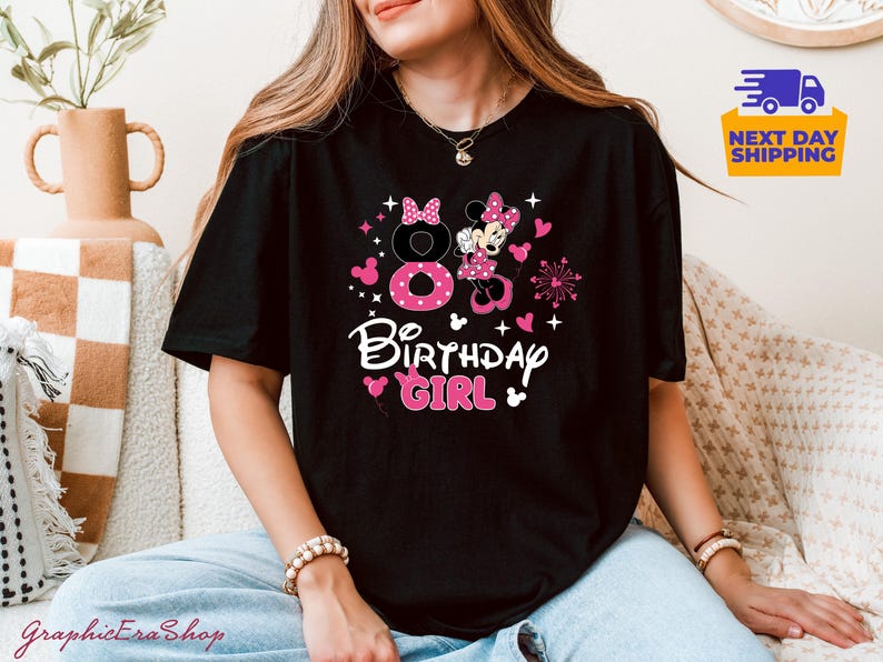 K&ouml;nnte beinhalten: Schwarzes T-Shirt mit einem rosa und wei&szlig;en Minnie-Maus-Design. Das Design umfasst die Zahl 8, Herzen, Sterne und die Worte "Birthday Girl". Das Shirt ist ein l&auml;ssiger Stil.