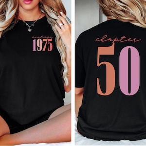 May include: Black t-shirt with a pink and orange graphic that says "vintage 1975" on the front and "chapter 50" on the back.