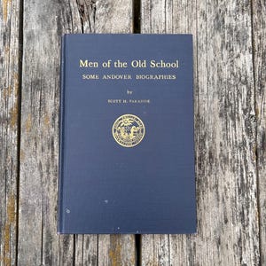 Może przedstawiać: Ciemnoniebieska książka w twardej oprawie zatytułowana Men of the Old School: Some Andover Biographies autorstwa Scotta H. Paradise'a. Na przedniej okładce znajdują się złote napisy oraz okrągły złoty emblemat z pieczęcią pośrodku.