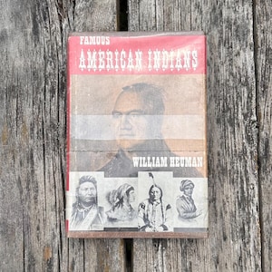 Puede incluir: Un libro de tapa dura titulado Famous American Indians de William Heuman. La portada presenta un gran retrato de un hombre en el centro, con cuatro retratos hist&oacute;ricos en blanco y negro m&aacute;s peque&ntilde;os debajo del nombre del autor.