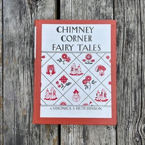 May include: A hardcover book titled Chimney Corner Fairy Tales by Veronica S. Hutchinson. The cover is orange with a white central panel featuring a black and red diamond pattern containing illustrations of castles, flowers, and royal figures.