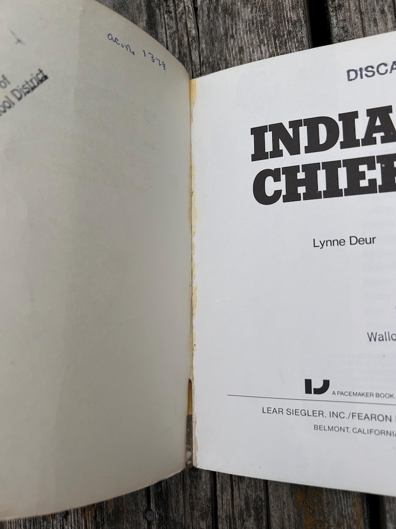 Może przedstawiać: Otwarte strony książki zatytułowanej Indian Chiefs autorstwa Lynne Deur, wydanej przez Lear Siegler, Inc./Fearon w Belmont w Kalifornii. Na lewej stronie widoczny jest odręczny tekst i pieczątka, a na prawej tytuł oraz informacje o wydawcy.