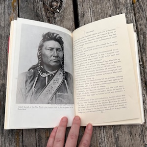 Puede incluir: Un libro abierto con un retrato en blanco y negro del Jefe Joseph de los Nez Perce en la p&aacute;gina izquierda y texto impreso en la derecha. El texto incluye el t&iacute;tulo Tecumseh y detalles sobre eventos hist&oacute;ricos y batallas.