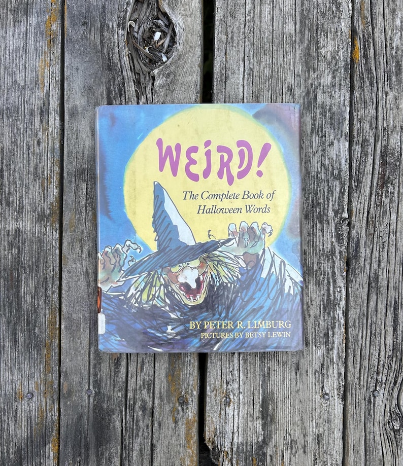 以下が含まれることがあります： ピーター・R・リンバーグ著、ベッツィ・リューイン絵のハードカバー本『Weird! The Complete Book of Halloween Words』。表紙には、大きな黄色い月を背景に、とんがり帽子をかぶった魔女のカラフルなイラストが描かれています。