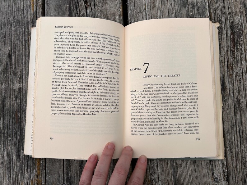 May include: An open book titled Russian Journey with cream-coloured pages and black text. The left page contains paragraphs of text, while the right page displays Chapter 7, Music and the Theater, with page numbers 154 and 155 visible at the bottom.