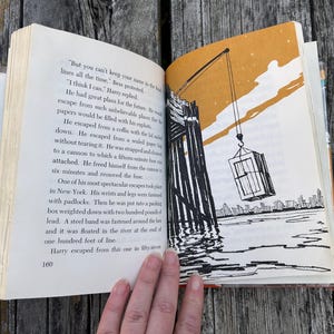 May include: An open book with cream-colored pages featuring black text and a black-and-white illustration of a crane lifting a crate over water. The page on the left is numbered 160 and contains text about escapes, while the right page shows a yellow sky.