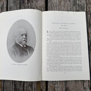 Może przedstawiać: Otwarta książka przedstawiająca czarno-biały portret Othniela Charlesa Marsha w owalnej ramce na lewej stronie oraz tekst biograficzny o paleontologu na prawej stronie, zawierający tytuł Othniel Charles Marsh 1831-1899.