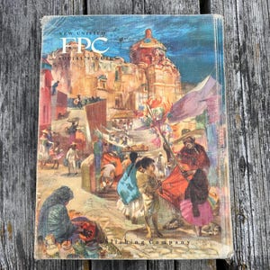 Może przedstawiać: Podręcznik w twardej oprawie zatytułowany New Unified FPC Social Studies wydawnictwa Follett Publishing Company. Okładka przedstawia kolorową ilustrację tętniącego życiem placu miejskiego z ludźmi w tradycyjnych strojach, dużym kamiennym budynkiem i kopułą.
